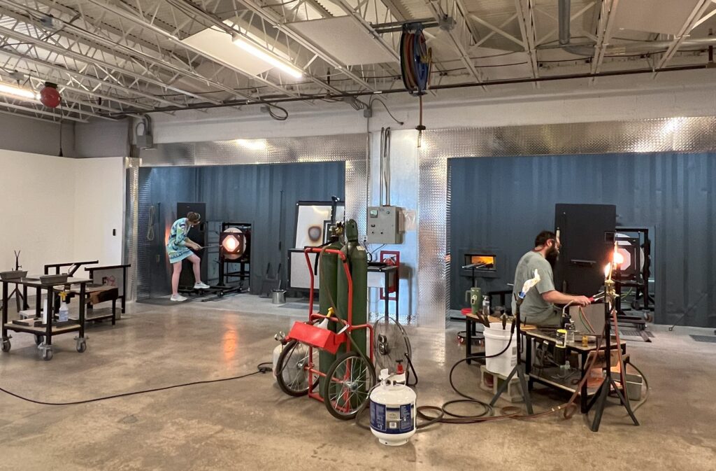 people blowing glass in a studio