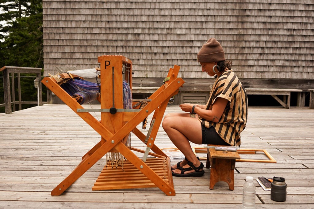 an artist at work on a loom